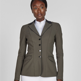 Woman wearing a green equestrian jacket on a plain background