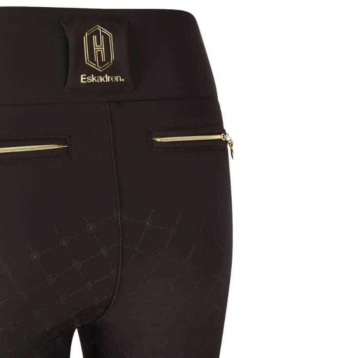 Close-up of black riding pants with gold zippers and Eskadron logo on a white background