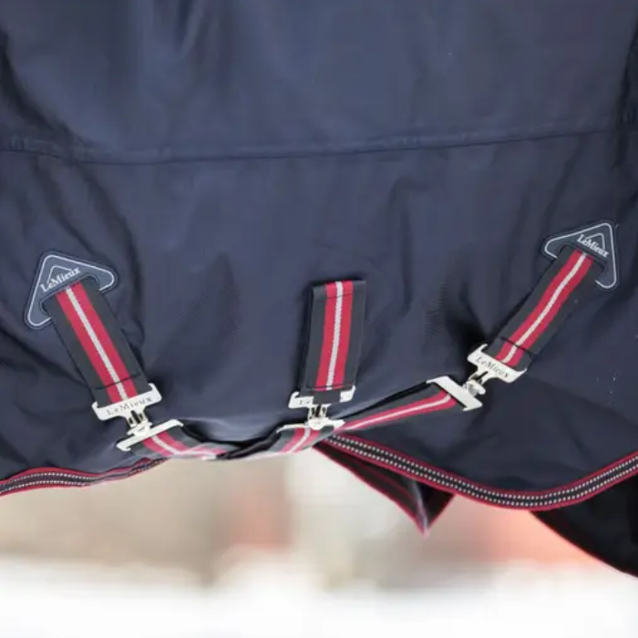Underside closure of a navy blue turnout rug with red straps