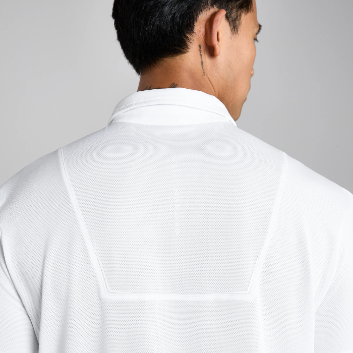 Person wearing a white polo shirt with a plain background