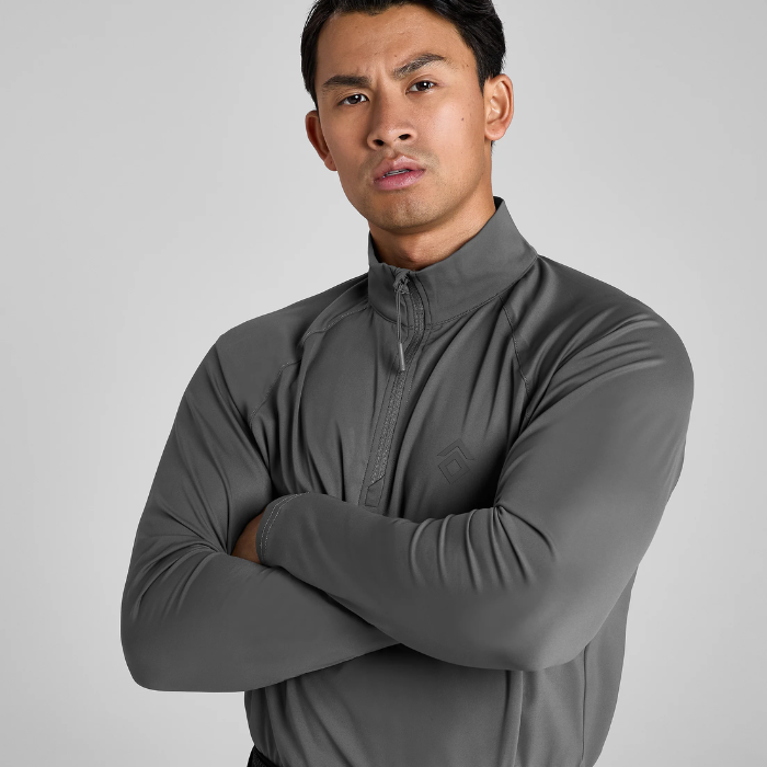 Man wearing a grey long-sleeve shirt against a plain background