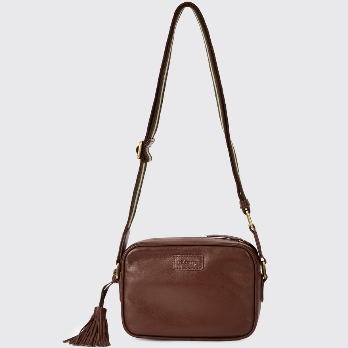 Brown leather crossbody bag with a tassel on a light grey background