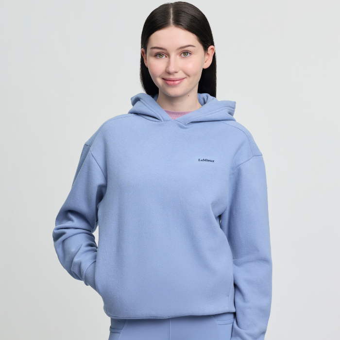 Person wearing a light blue hoodie with a brand logo on a plain background