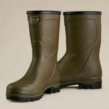 Pair of green rubber boots with black soles on a beige background