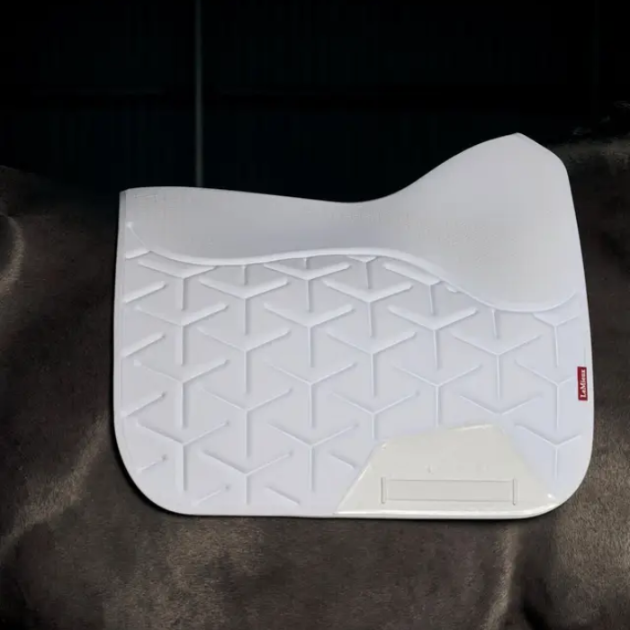 White textured saddle pad on a horse against a dark backgrounf