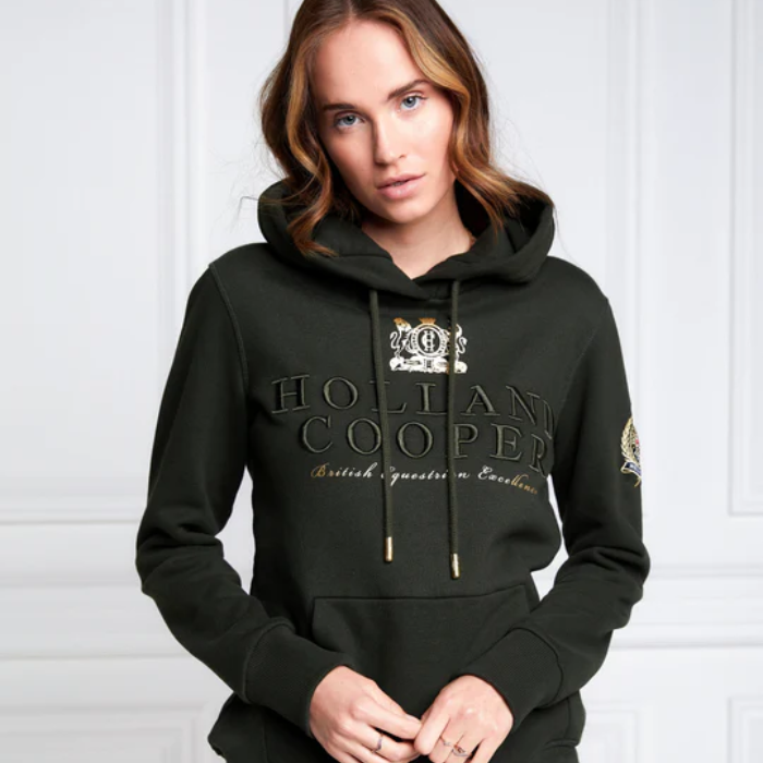 Person wearing a dark green hoodie with 'Holland Cooper' branding against a white background