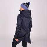 Person wearing a dark winter coat and a matching beanie on a light grey background