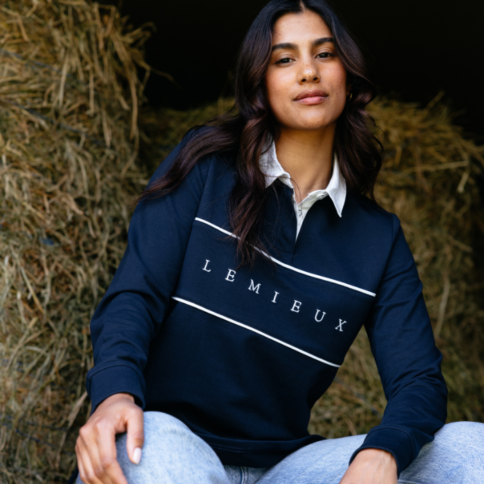 Person wearing a navy blue 'LEMIEUX' sweatshirt sitting against a hay bale.