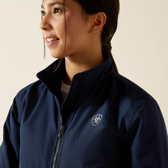 Close-up of a blue jacket with zipper and white branding on a beige background