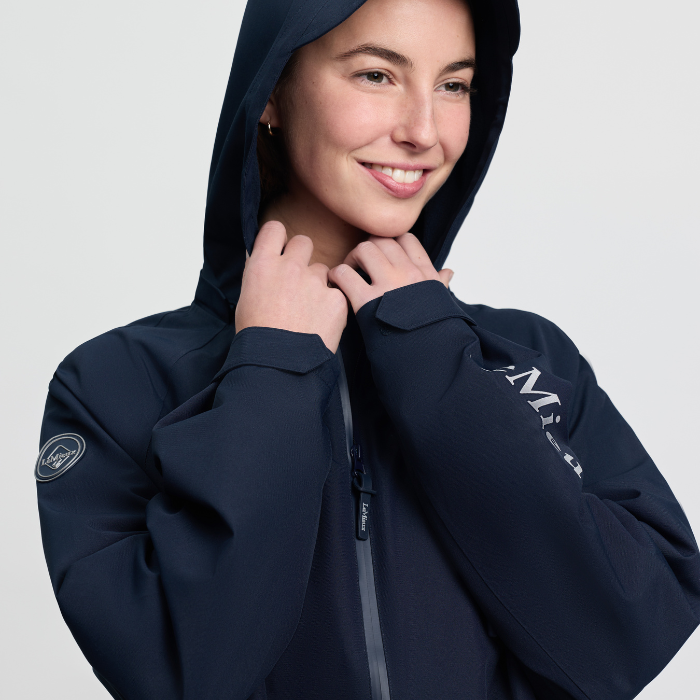 Woman wears a navy hooded jacket on a white background