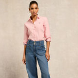 Woman wearing a pink shirt and blue flared jeans on a beige background