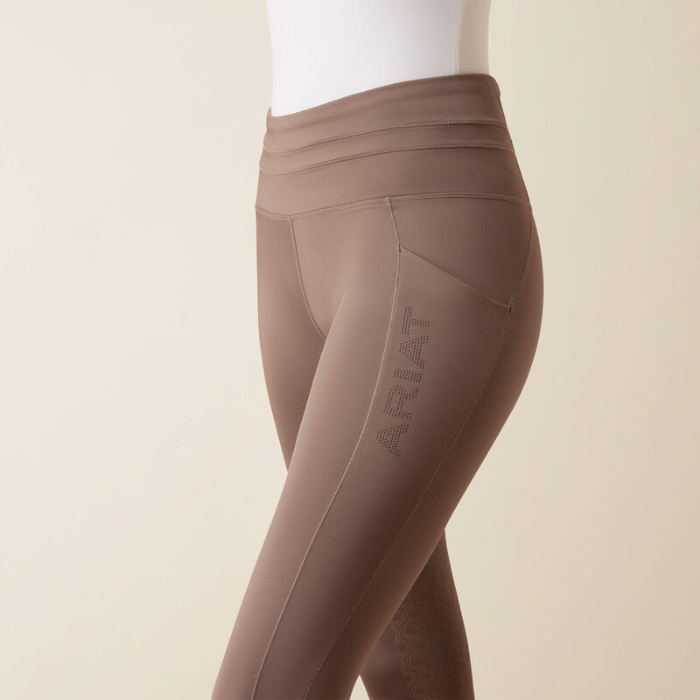 Pair of brown riding tights with ARIAT branding on a beige background