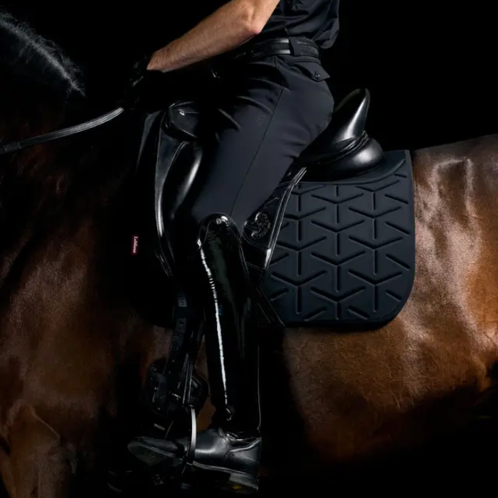 Rider sits in a saddle against a dark background