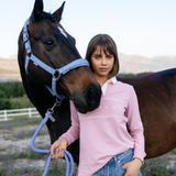Girl in pink shirt standing next to a horse in an outdoor setting
