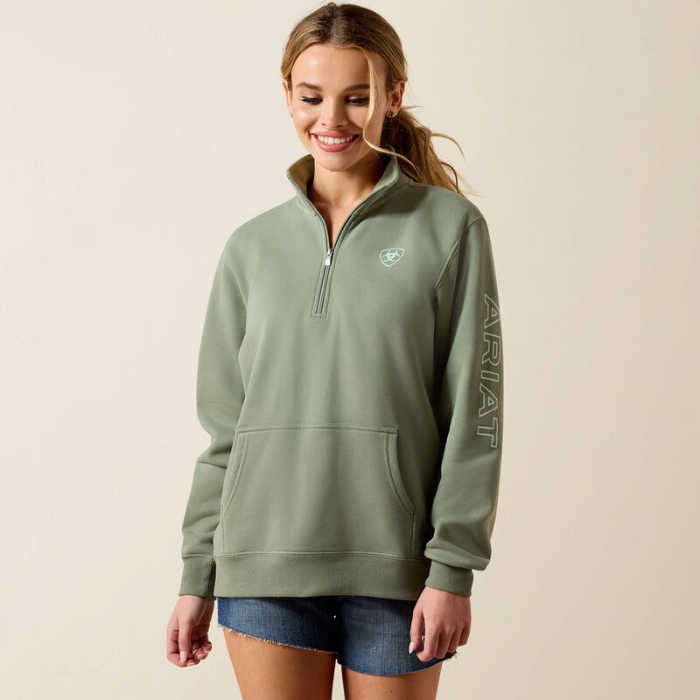 Woman wearing a green Ariat sweatshirt on a beige background
