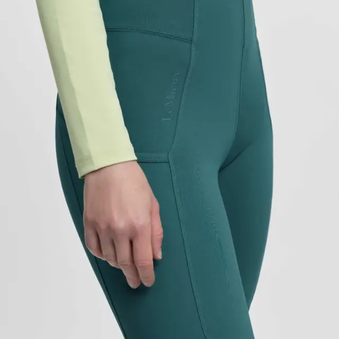Teal leggings with a light green long-sleeve shirt on a white background