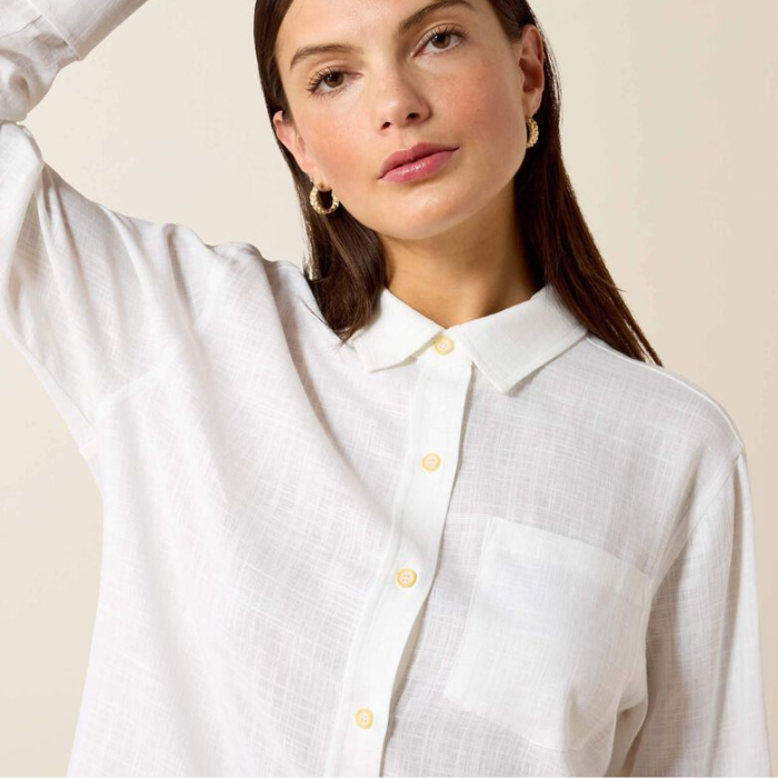 Woman wears a white linen shirt on a beige background