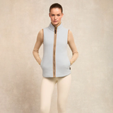 Woman wears a light blue fleece gilet and neutral top on a plain background