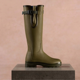 Green wellington boot on a podium against a brown background