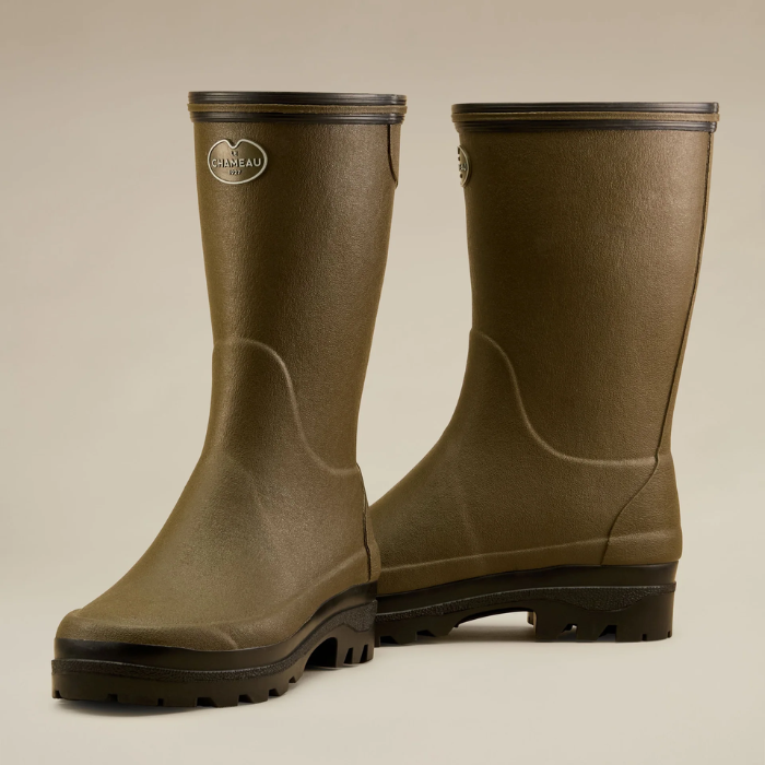 Pair of green rubber boots on a beige background