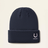 Navy beanie hat with horseshoe emblem and ARIAT branding on a beige background