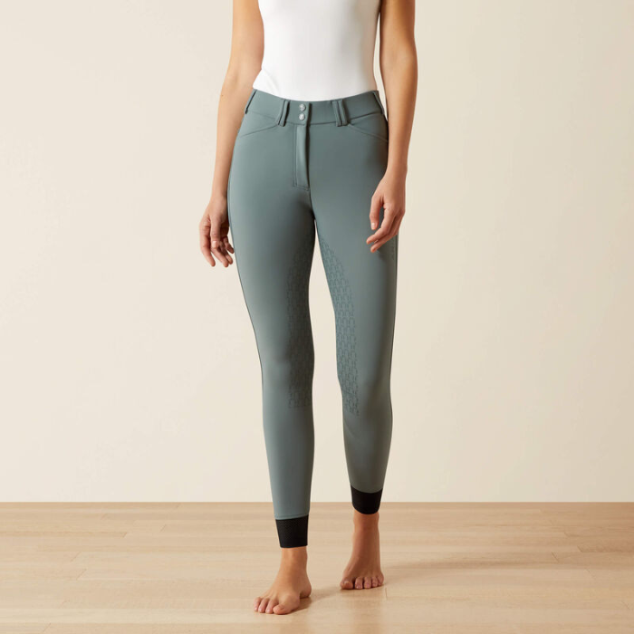 Person wearing teal riding pants on a plain background