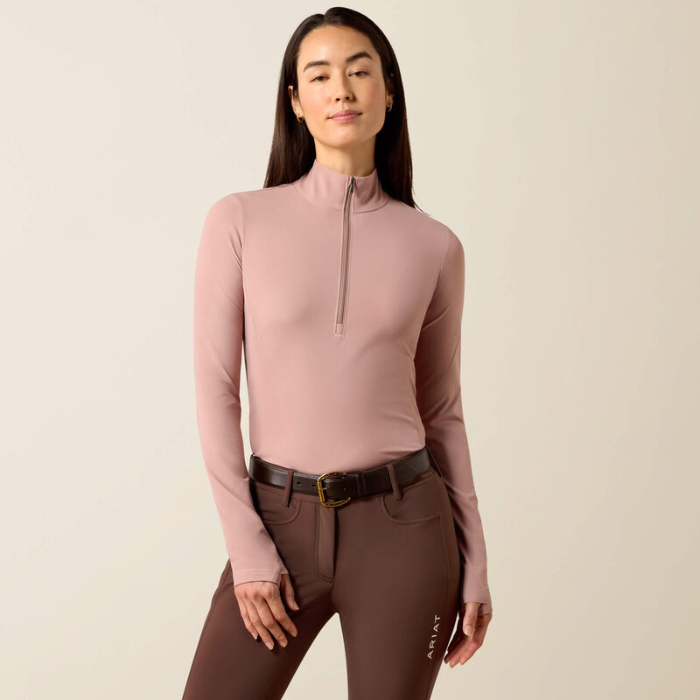 Soft pink riding top with brown leggings on a beige background
