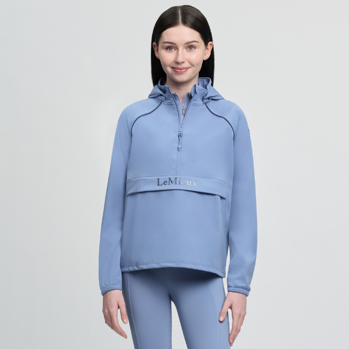 Woman wearing a blue hoodie with a visible brand logo on a light grey background