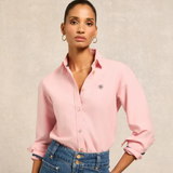 Woman wearing a pink shirt with a logo on a beige background