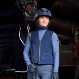 Woman wears an equestrian outfit complete with helmet in a dark setting