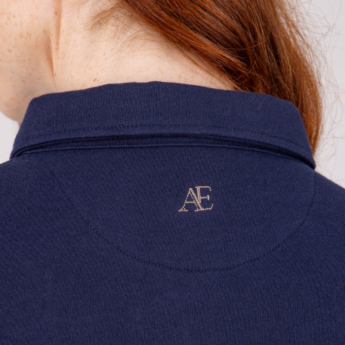 Navy blue polo shirt with a logo on the collar against a neutral background