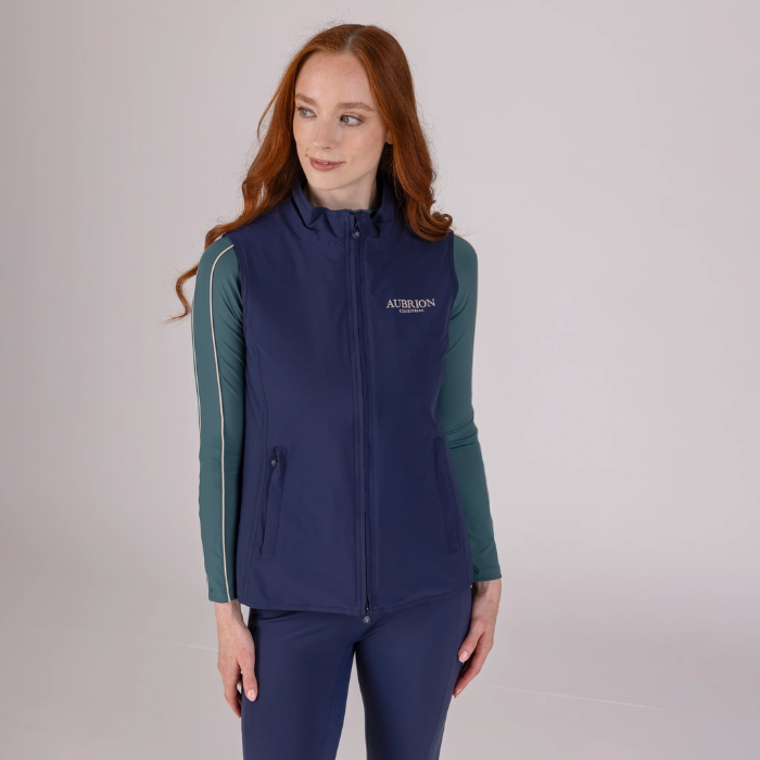 Woman wearing a navy blue gilet with a visible brand logo on a light grey background