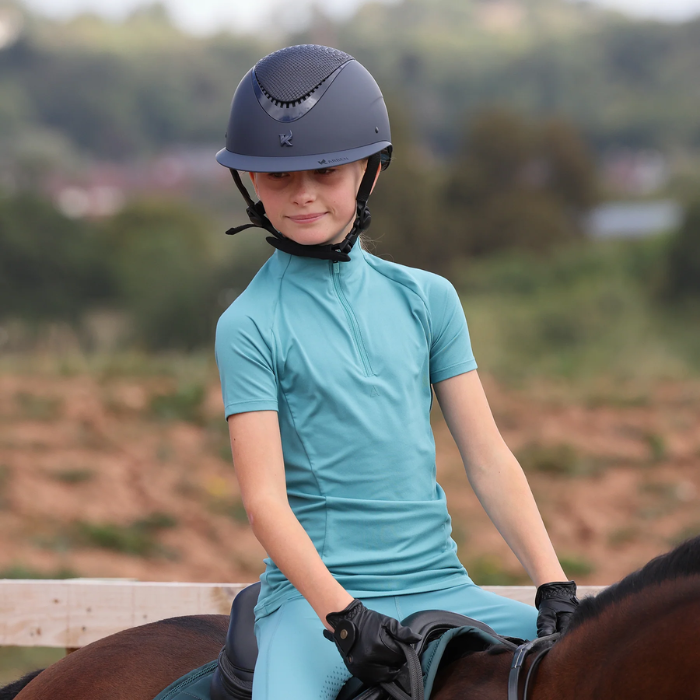 Person in equestrian gear sitting on a horse with a blurred natural background