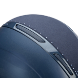 Close-up of a vavy blue riding hat with diamante detailing  and air vents on a white background