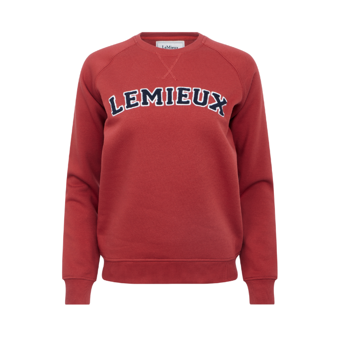 LeMieux AW26 Vida Varsity Crew Neck Sweat Variant Colour Russet.
A red crewneck sweatshirt with 'LEMIEUX' printed across the chest in navy blue and white varsity-style lettering, shown on a plain white background.