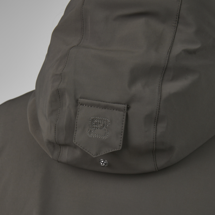Close-up of a dark green jacket with a pocket and brand logo on a light grey background